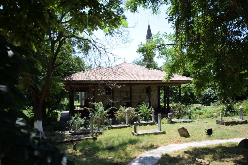 The historic Esmahan Sultan Mosque in Mangalia, Romania, surrounded by trees and its centuries-old Muslim cemetery.